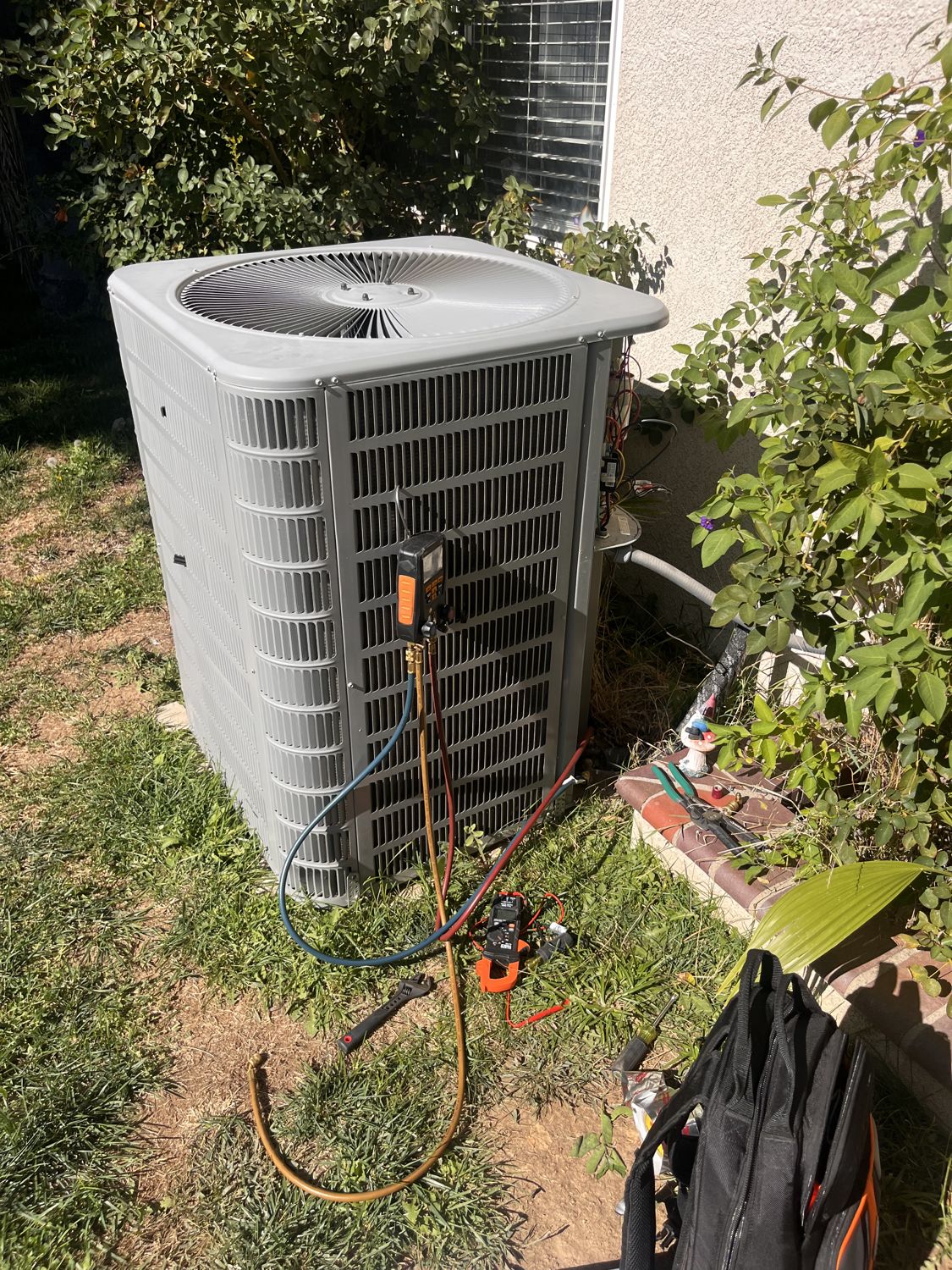 HVAC technician gauges connected to an outdoor AC unit during a service call